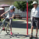 photo of adult student learning how to "power pedal" her bicycle as instructor looks on