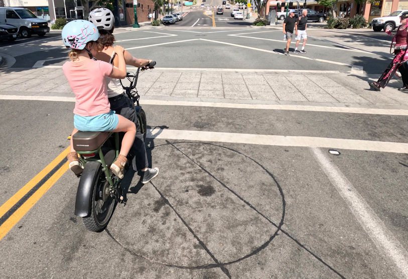 Two cyclists on an ebike waiting on a round loop detector